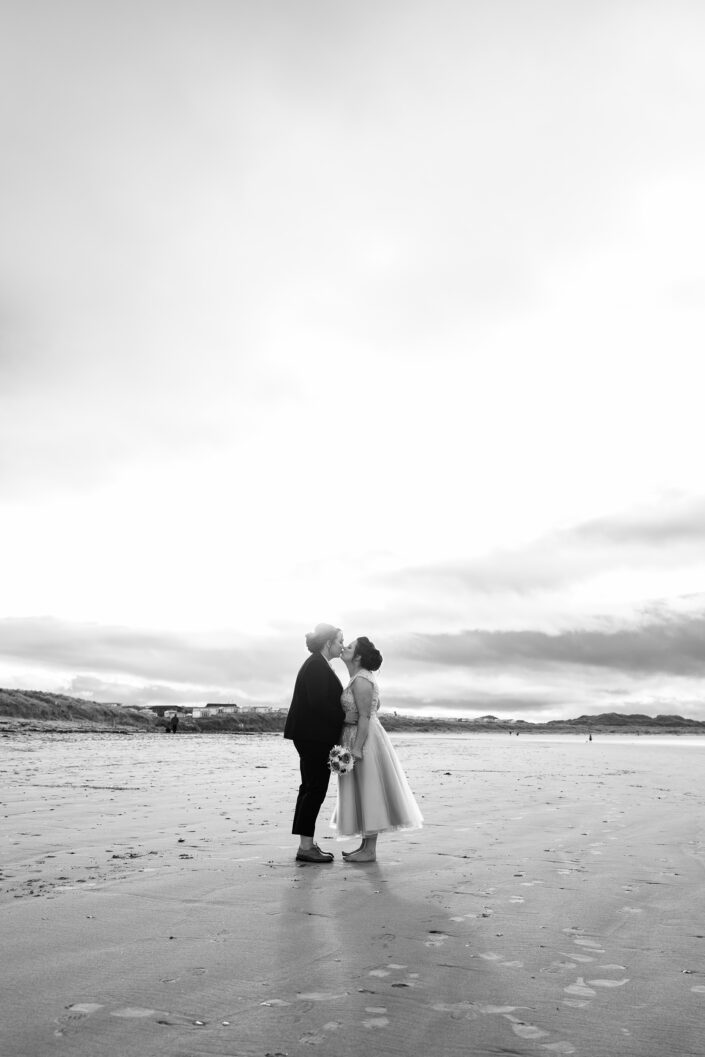 two brides kissing on beach